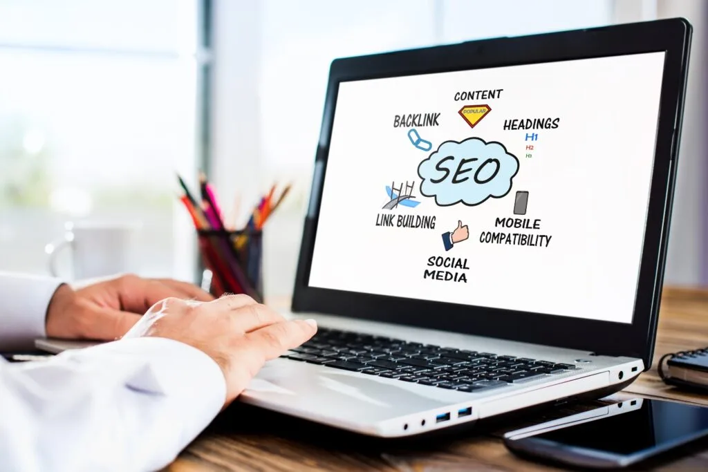 Hands using a laptop with an SEO icon on the screen