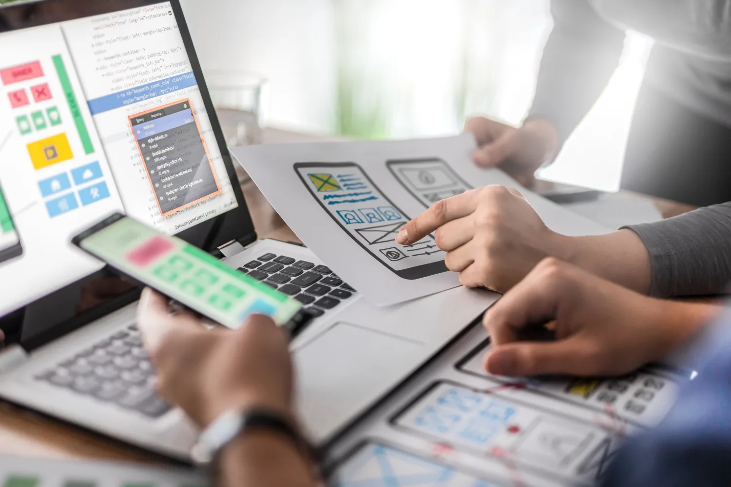 finger pointing at a printed web design copy while another hand holds a phone